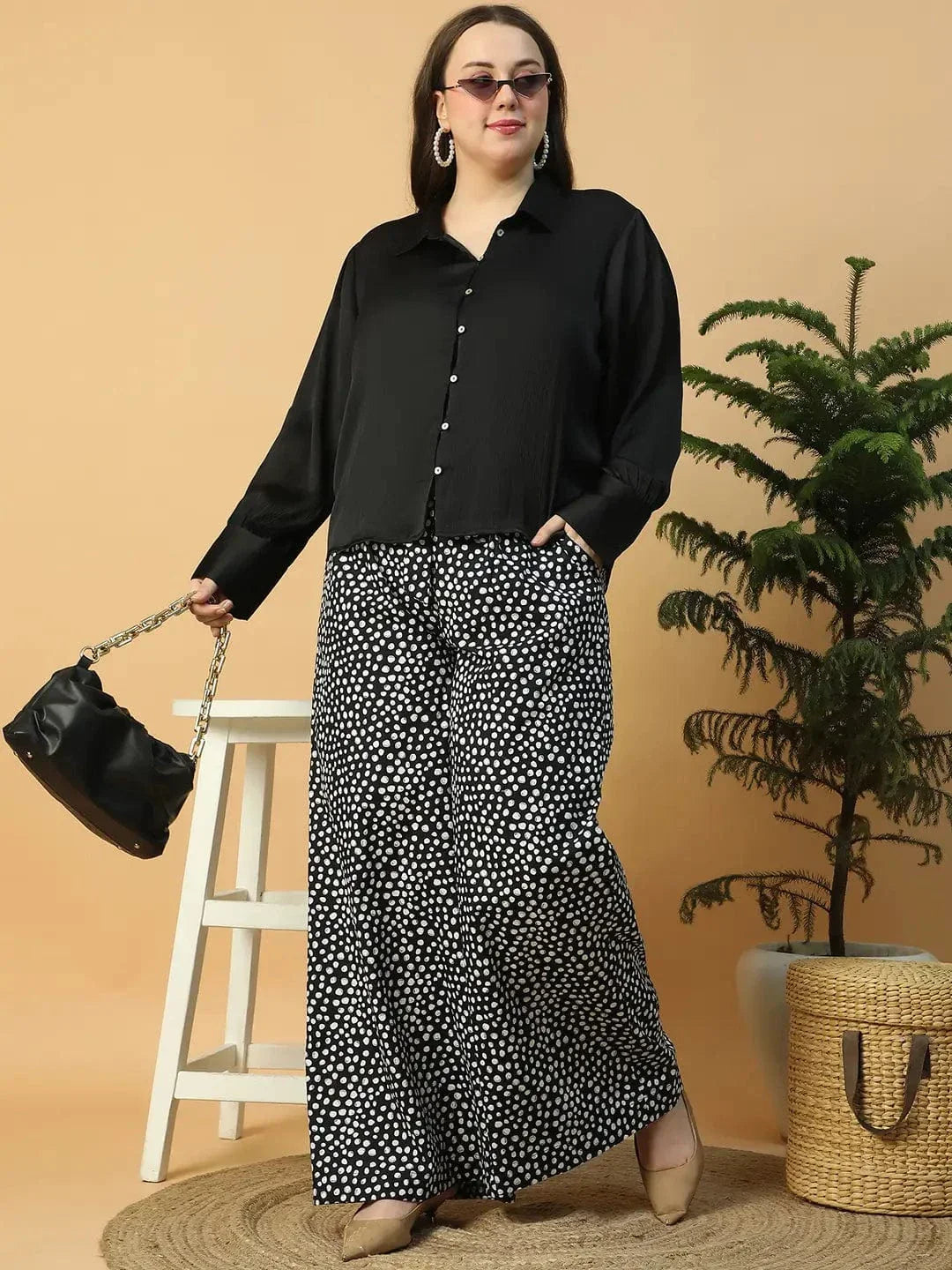 A person wearing wide-leg pants with a black and white polka dot pattern.