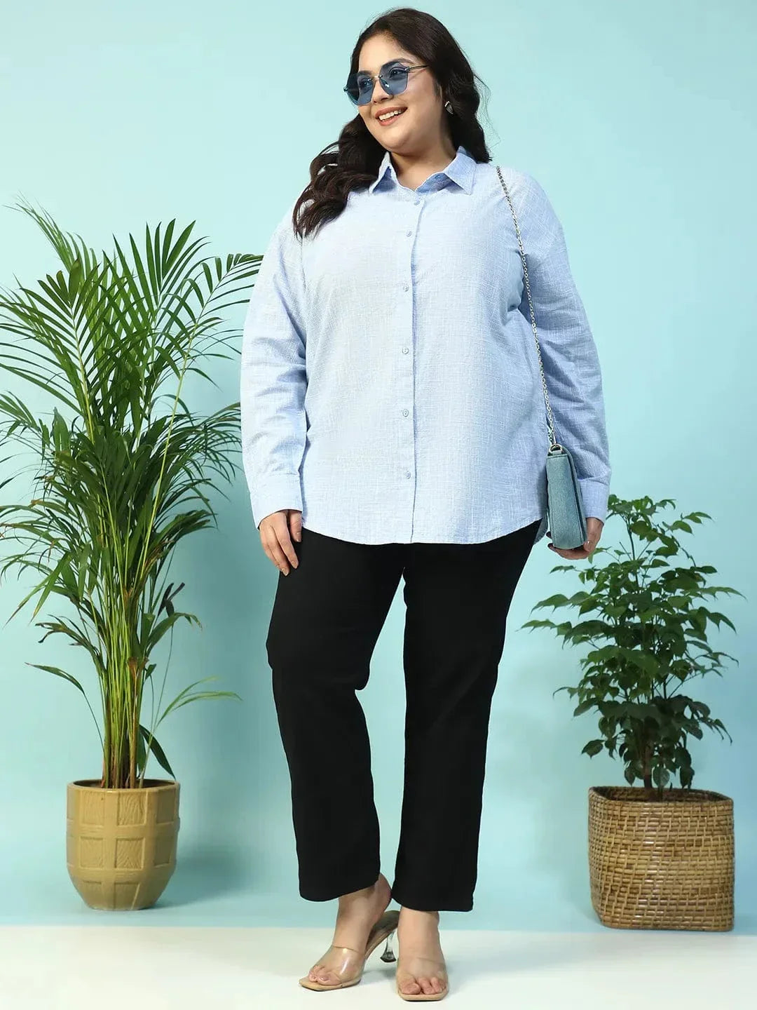A smiling woman with long dark hair wearing a light blue button-up shirt.