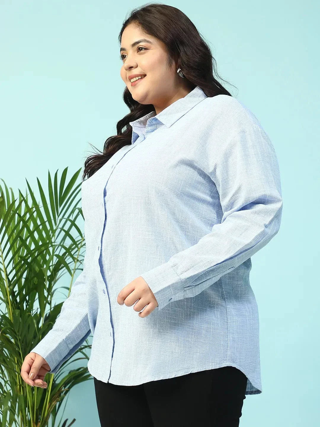 A smiling woman with long dark hair wearing a light blue button-up shirt.