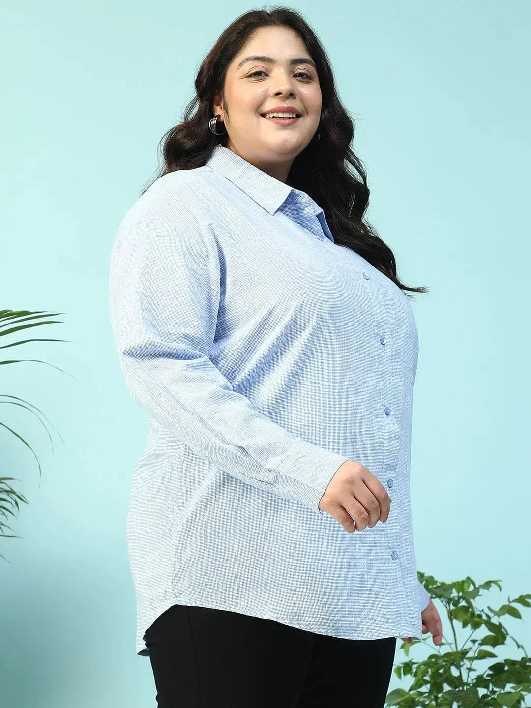 A smiling woman with long dark hair wearing a light blue button-up shirt.