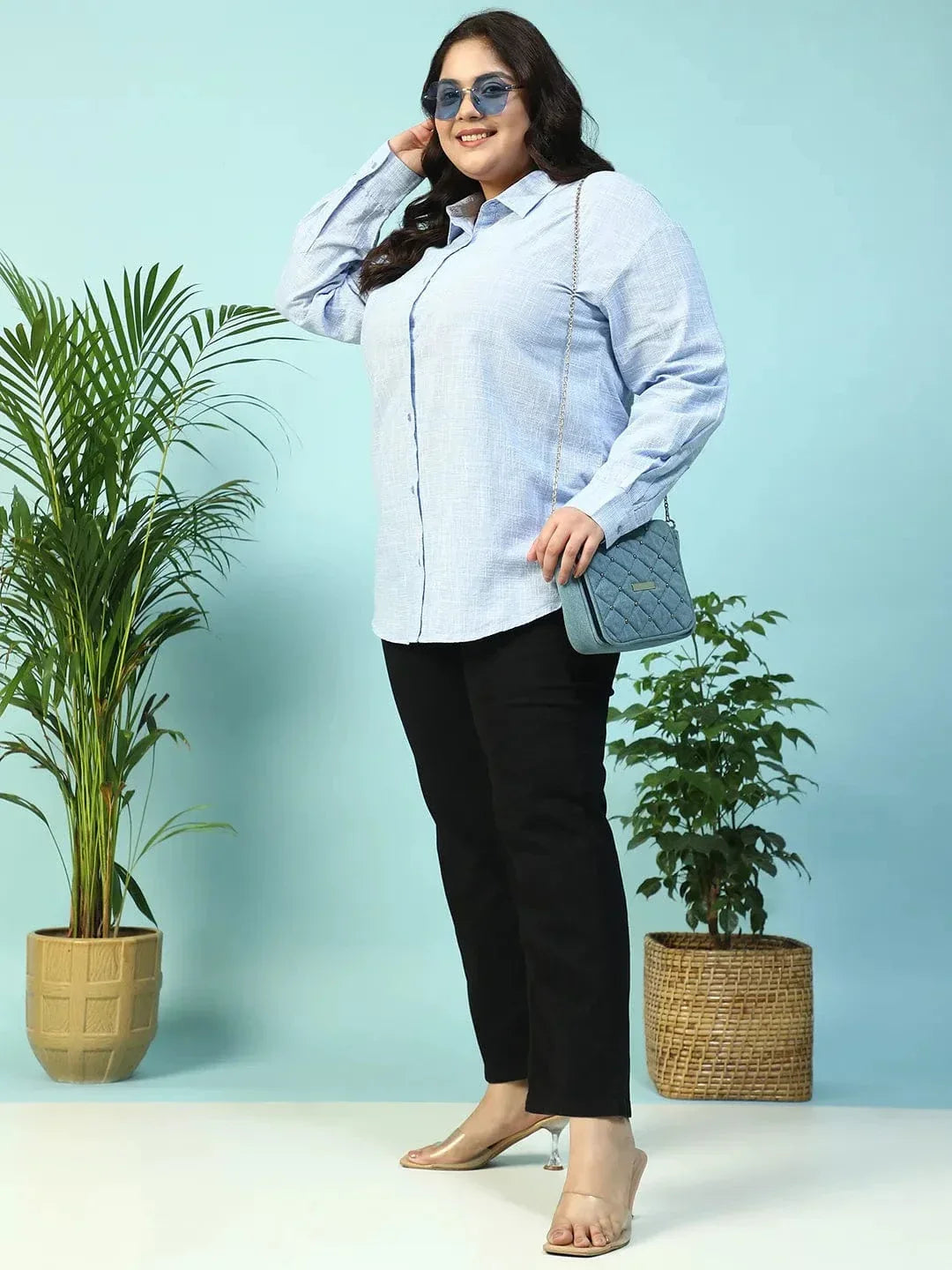 A smiling woman with long dark hair wearing a light blue button-up shirt.