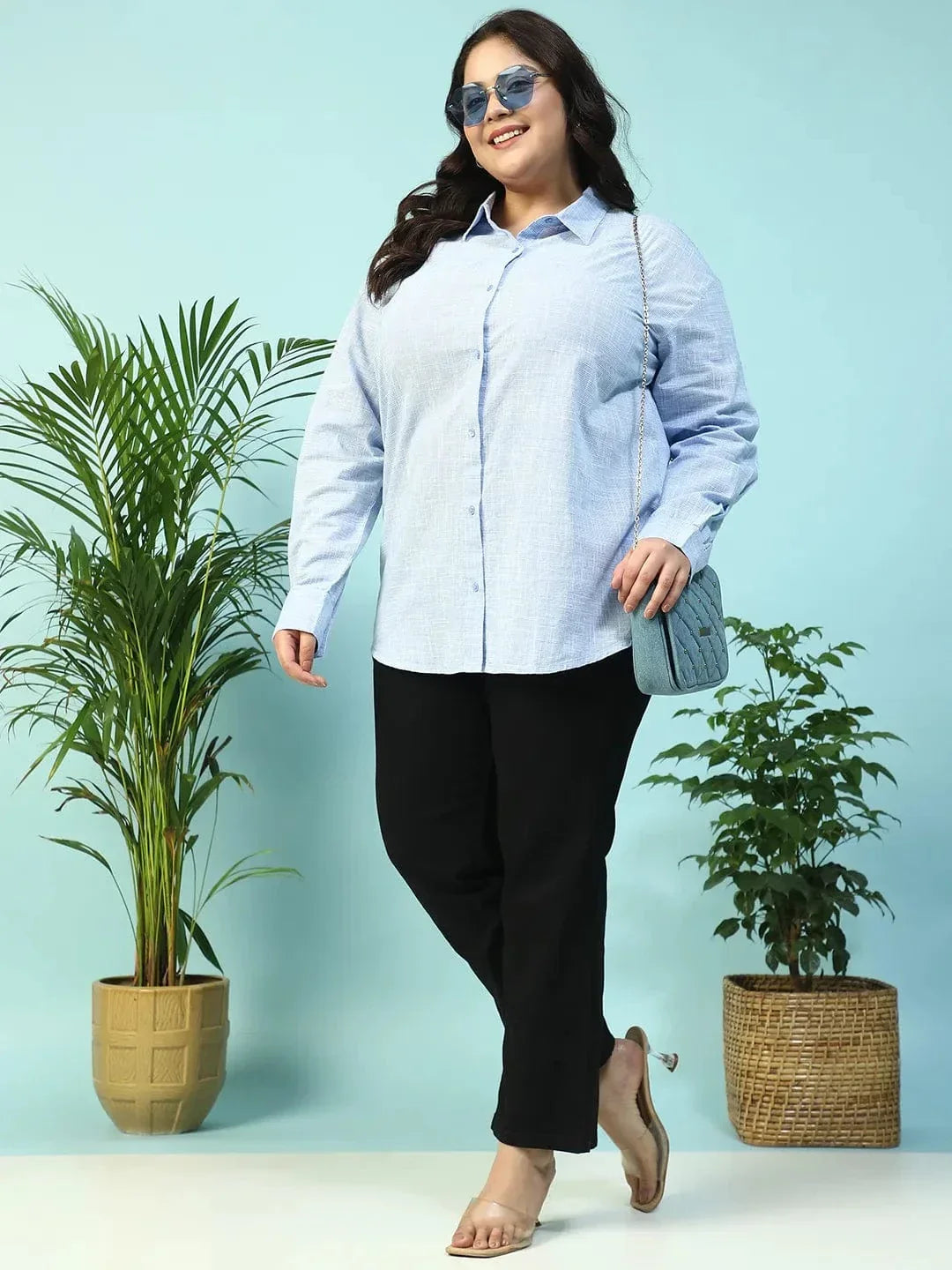 A smiling woman with long dark hair wearing a light blue button-up shirt.