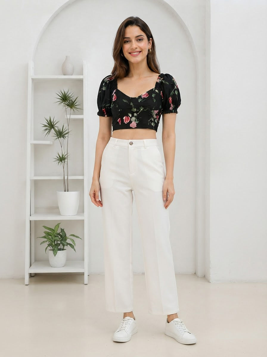Woman in black floral crop top with puff sleeves and white wide-leg pants, stylish plus size fashion outfit