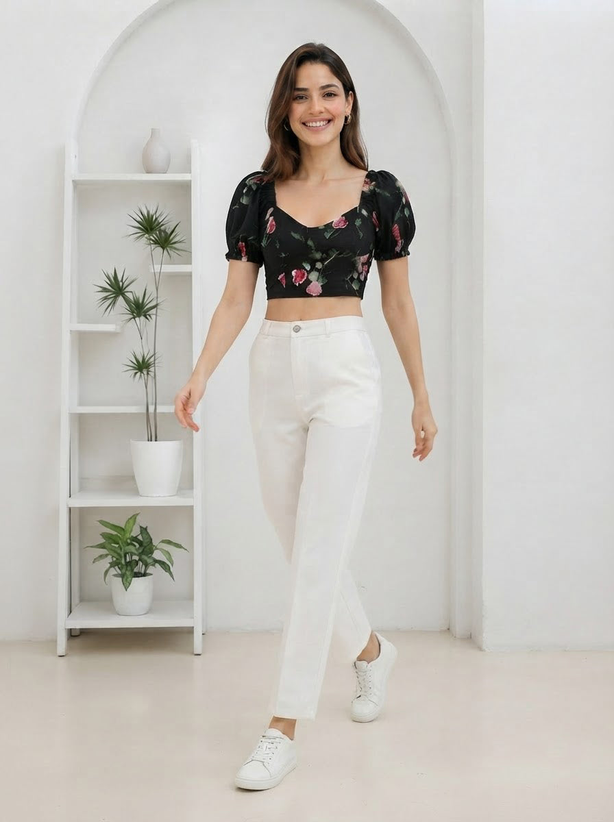 Woman in black floral crop top with puff sleeves, white high-waist pants, and white sneakers