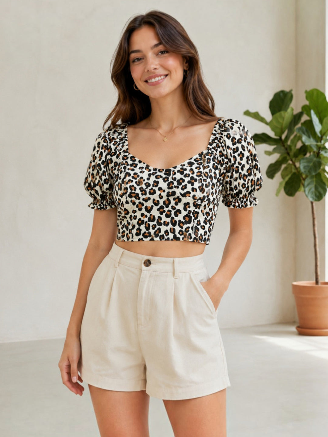 Woman in leopard print crop top with puff sleeves and cream high-waisted shorts, stylish summer outfit