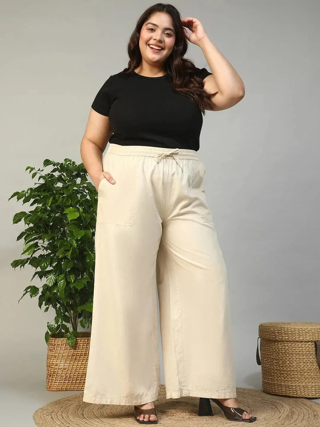 A person wearing a pair of wide-leg beige pants with a drawstring waist and high heels.