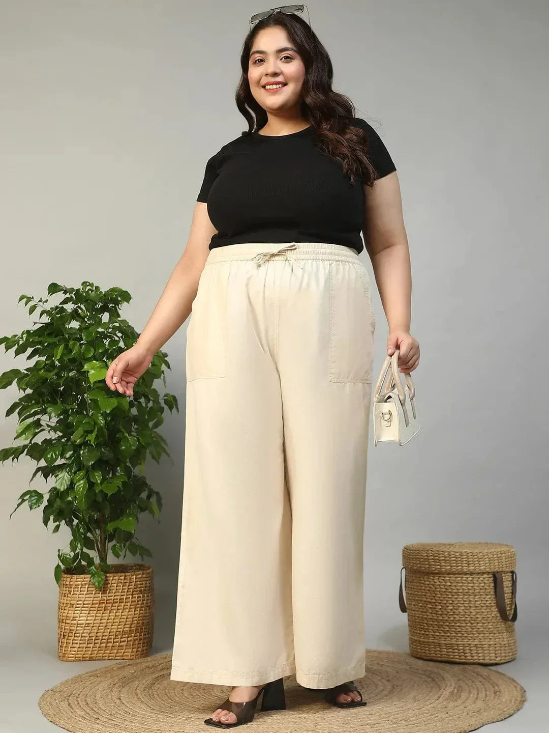 A person wearing a pair of wide-leg beige pants with a drawstring waist and high heels.