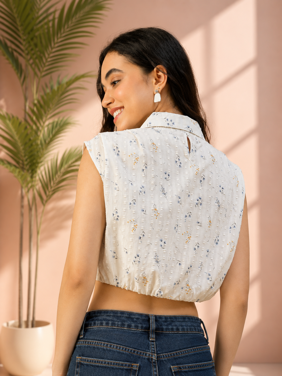 White floral sleeveless crop top with back keyhole detail, paired with denim jeans for trendy women's fashion