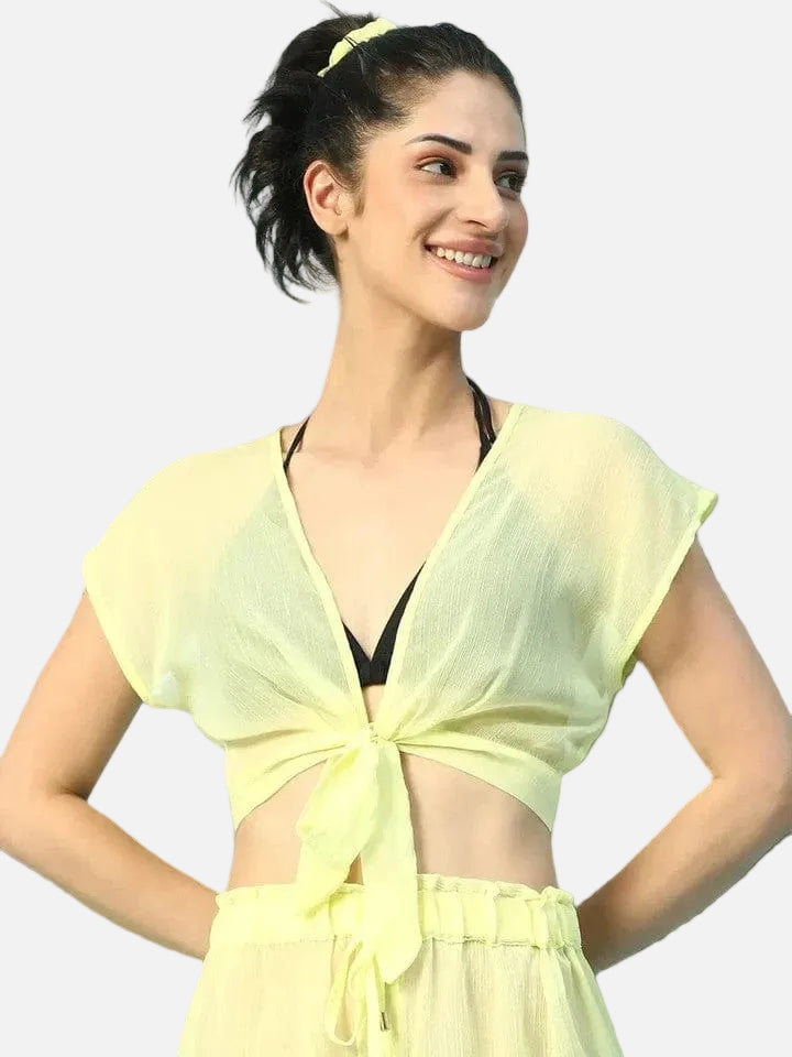 A woman wearing a yellow crop top and skirt is smiling and posing confidently.