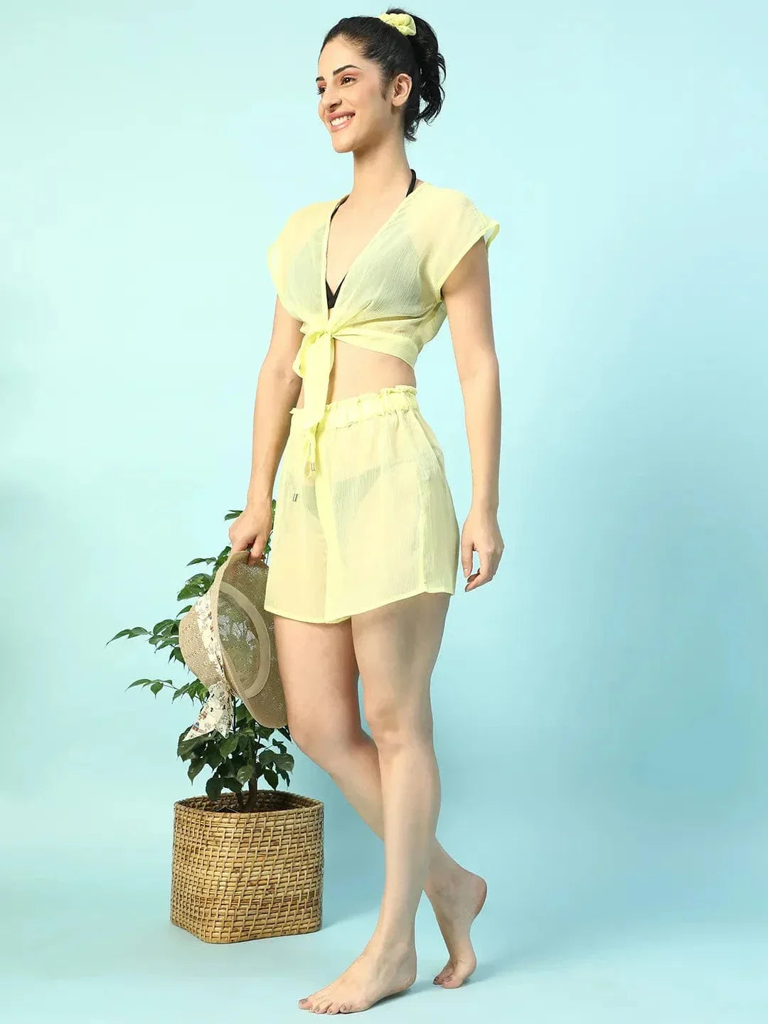 A woman wearing a yellow crop top and skirt is smiling and posing confidently.