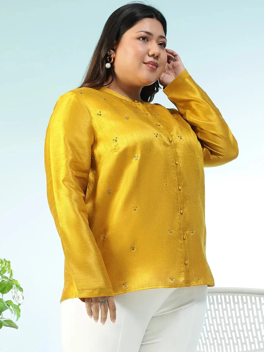 A woman wearing a yellow blouse with small embroidered designs, posing for a photograph.