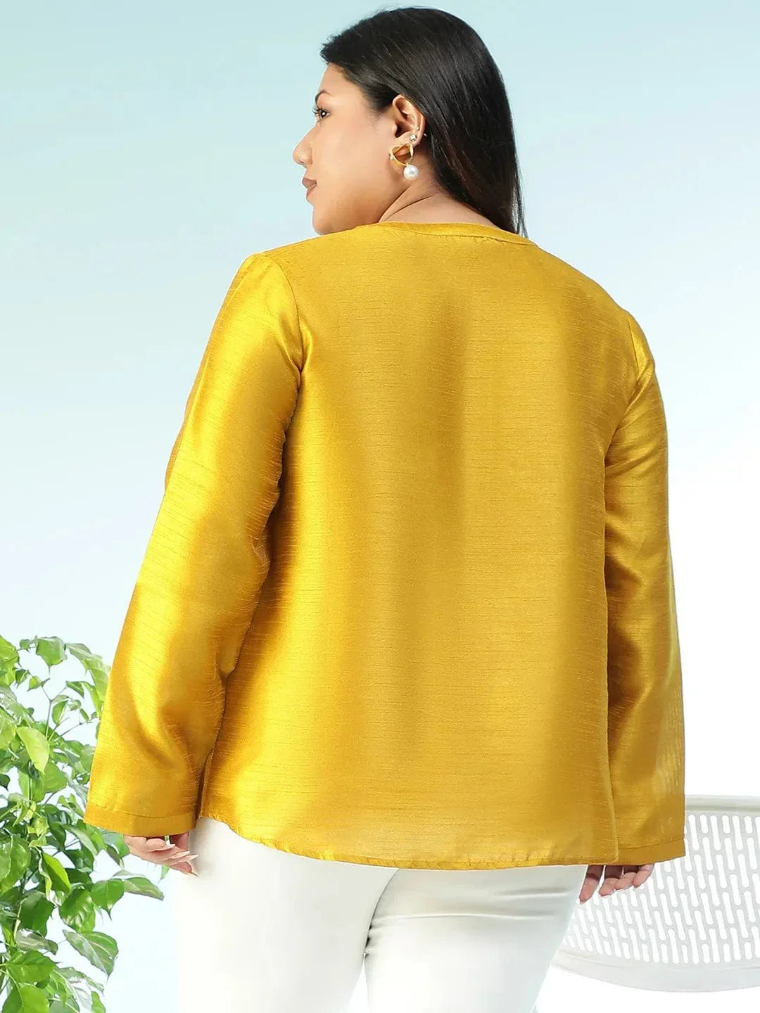 A woman wearing a yellow blouse with small embroidered designs, posing for a photograph.
