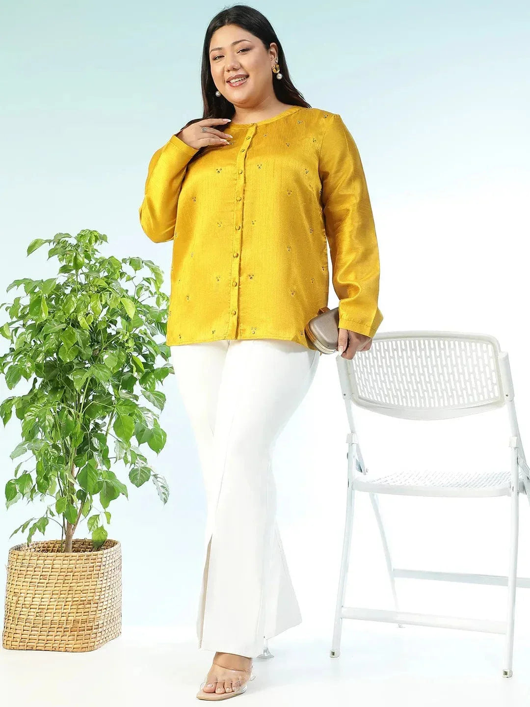 A woman wearing a yellow blouse with small embroidered designs, posing for a photograph.
