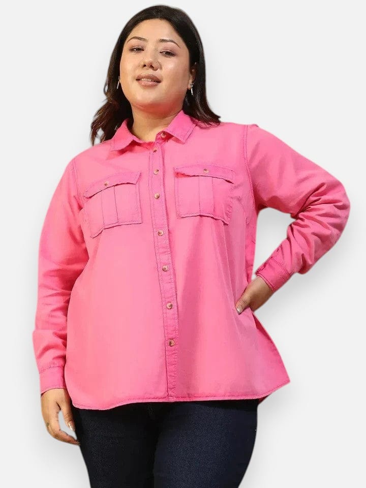 A woman wearing a bright pink button-up shirt with a collar and two pockets, standing against a white background.