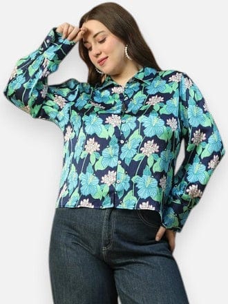 A woman wearing a floral print blouse and jeans is posing with her hand on her head.