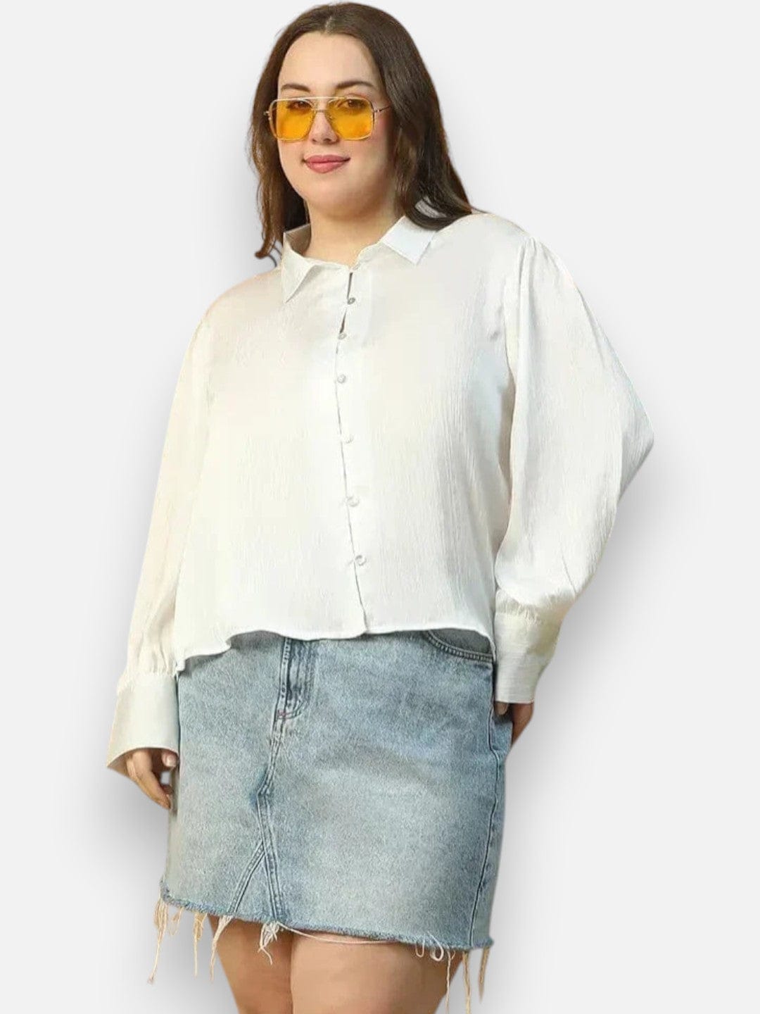 A woman wearing a white blouse and a denim skirt, with yellow sunglasses on her face.