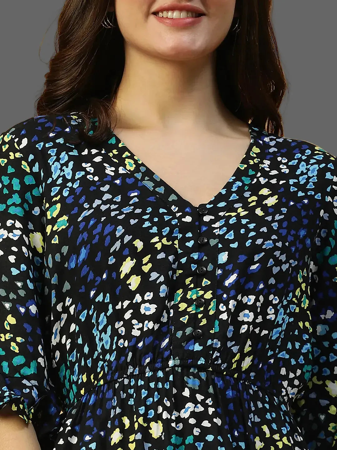 Woman wearing a black blouse with colorful abstract pattern against a beige background