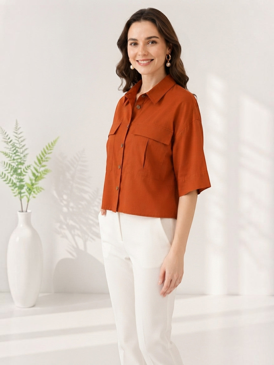 Rust orange button-up shirt with chest pockets, paired with white pants for women's fashion