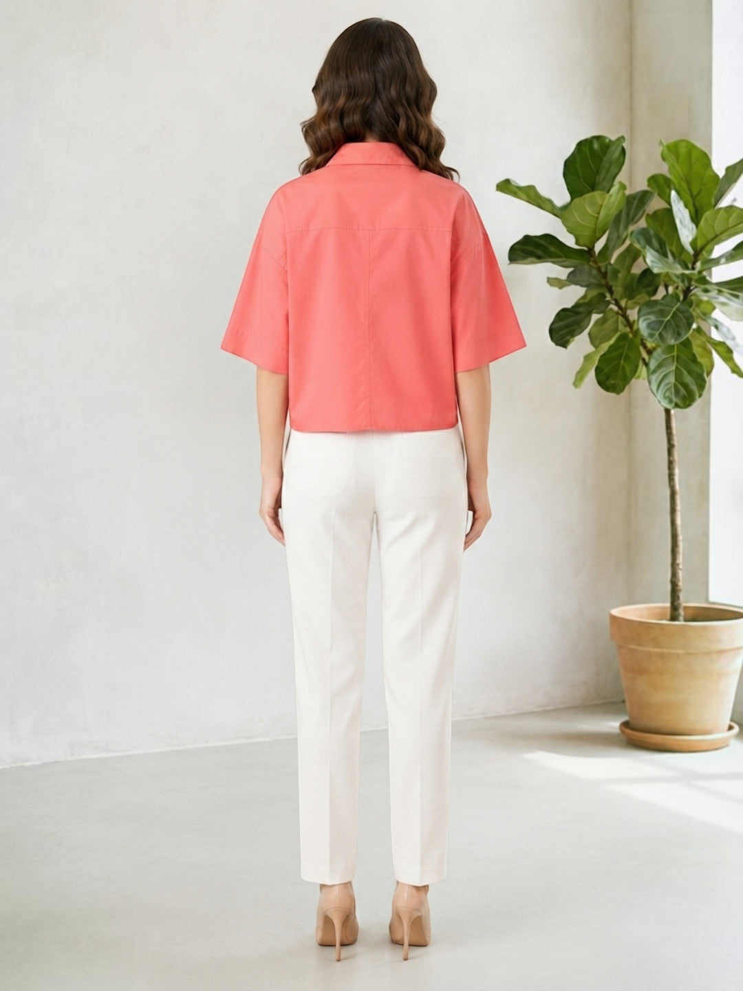 Woman in coral cropped shirt and white trousers, back view, modern office chic outfit