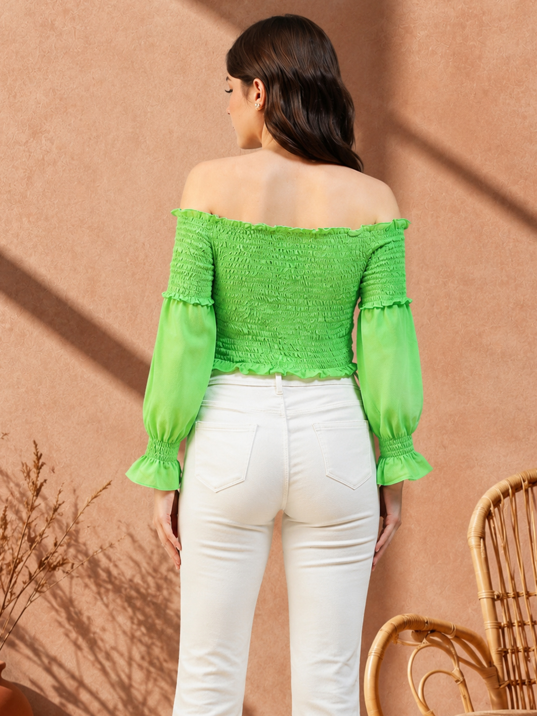Vibrant green off-shoulder ruched top with long sleeves, paired with white jeans for trendy women's fashion.