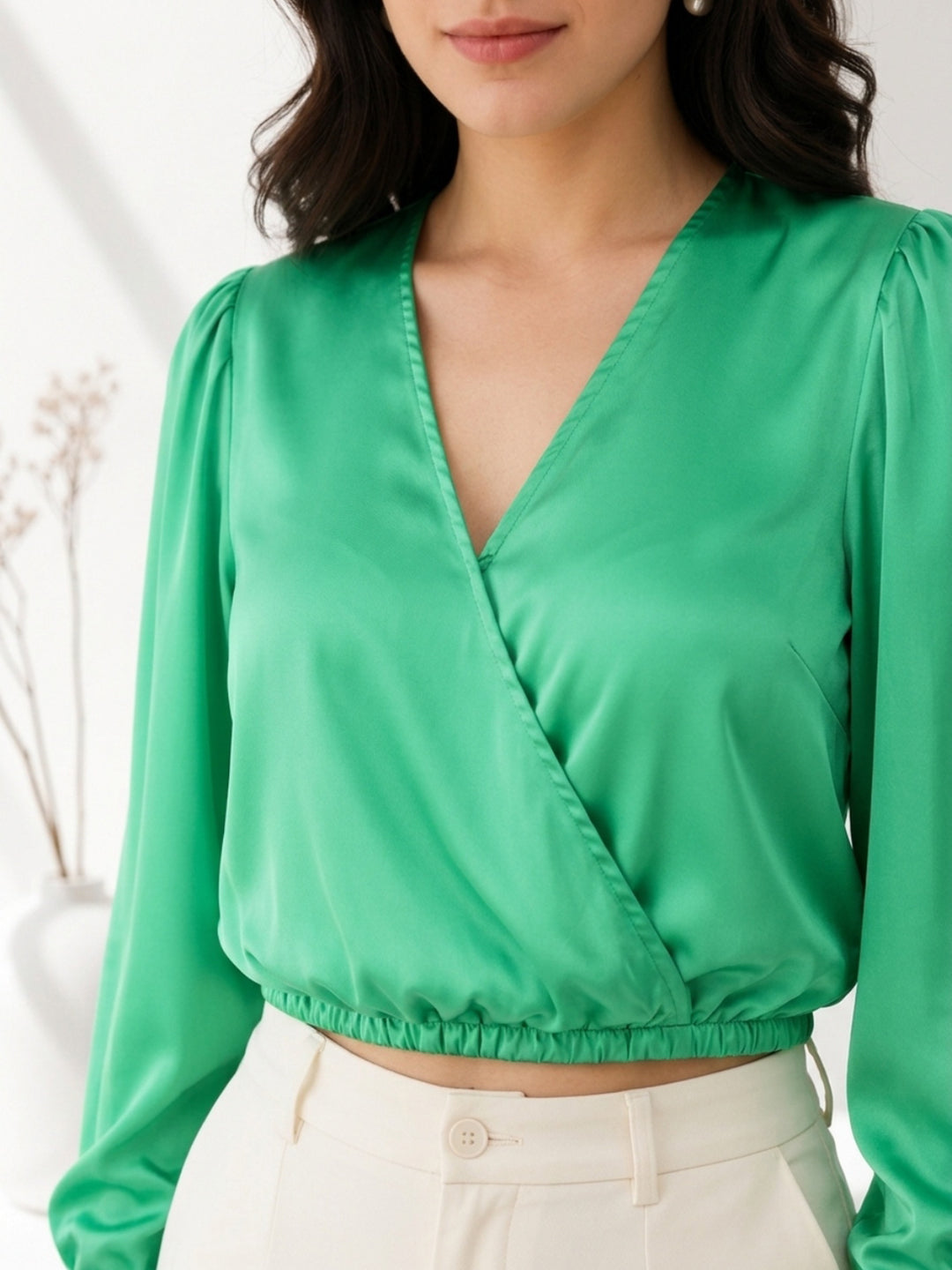 Emerald green satin wrap top with puff sleeves, paired with cream trousers for women's fashion