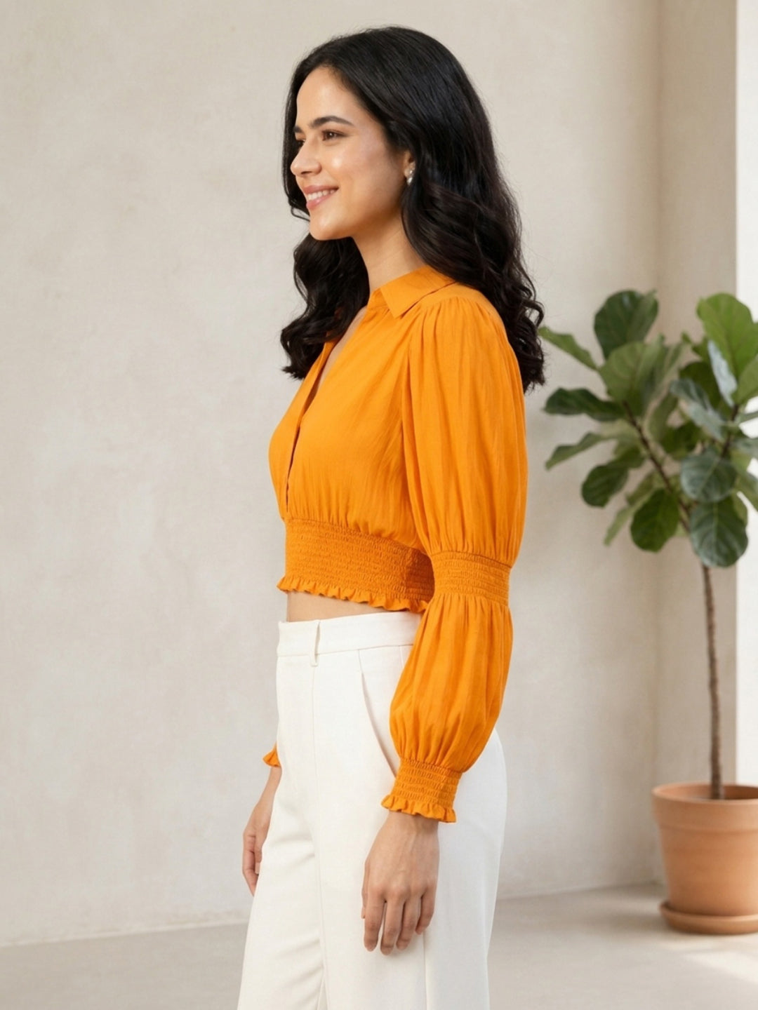 Woman in mustard yellow smocked crop top with puff sleeves, paired with white pants, stylish plus size fashion