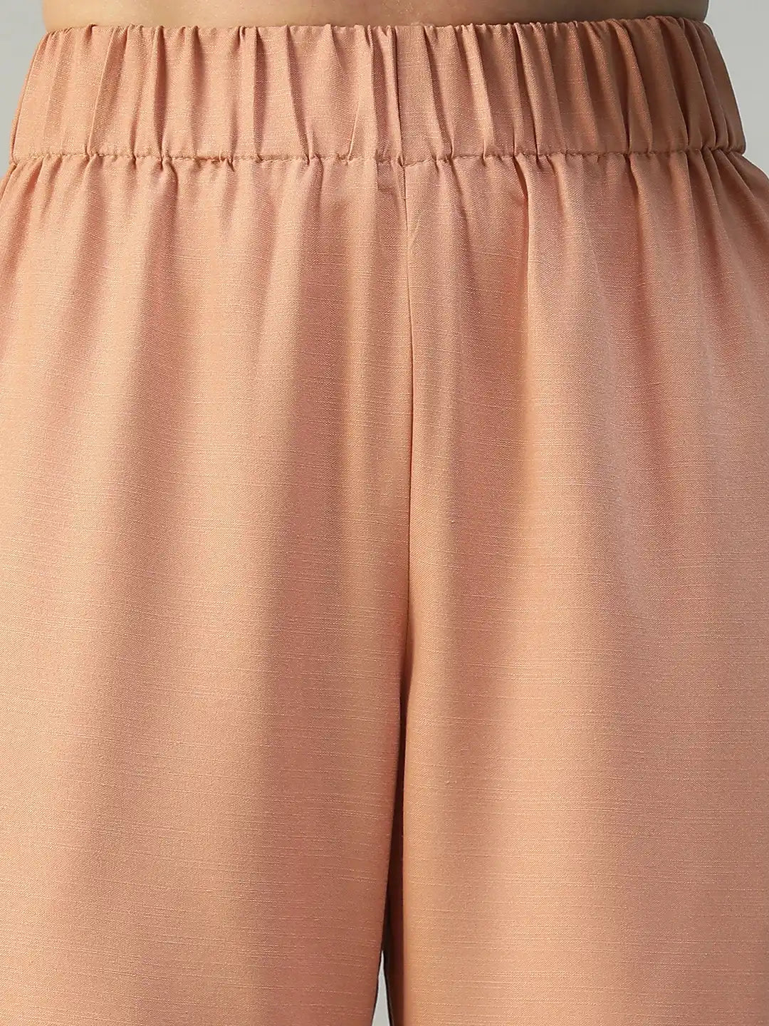Close-up of a pair of peach-colored pants with an elastic waistband.