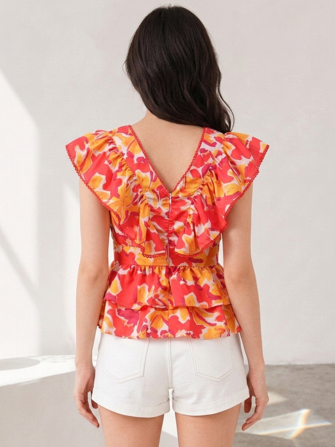 Floral ruffle top with V-back, plus size women's fashion, vibrant orange red print, paired with white shorts