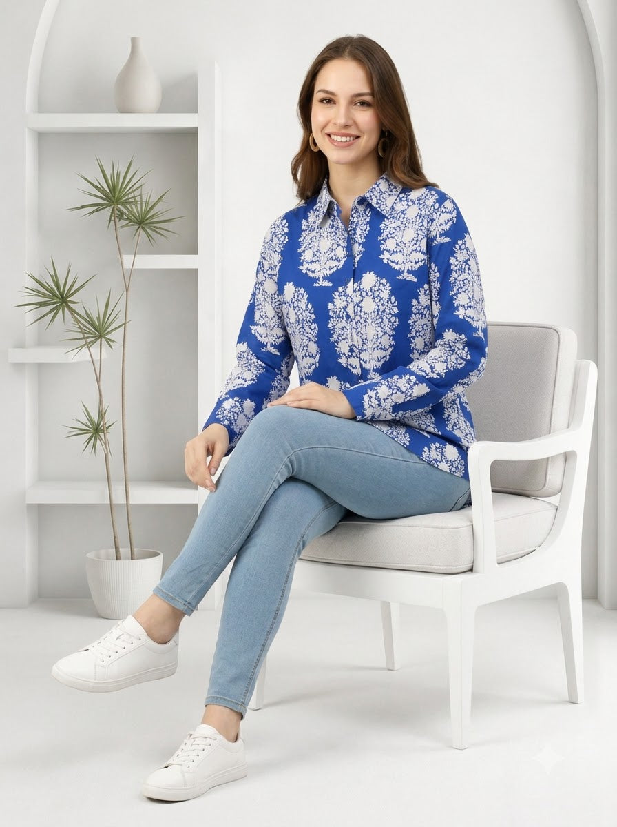 Woman in blue floral print shirt, light jeans, white sneakers, sitting on white chair