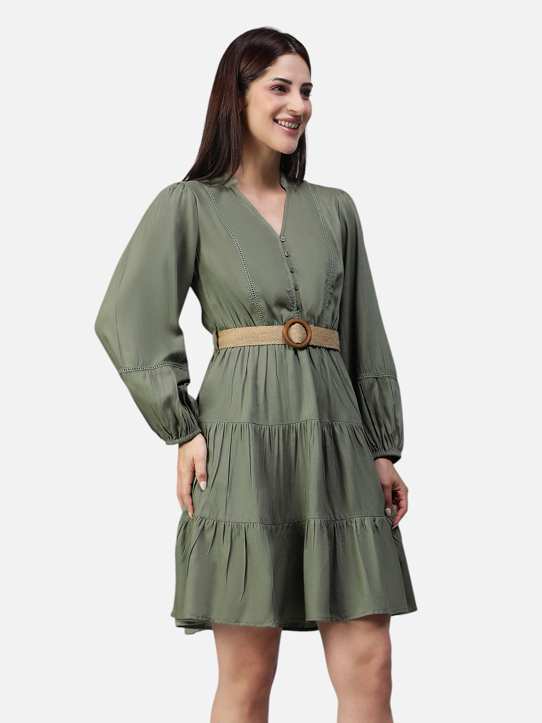 Woman wearing an olive green tiered mini dress with long sleeves and a beige belt.