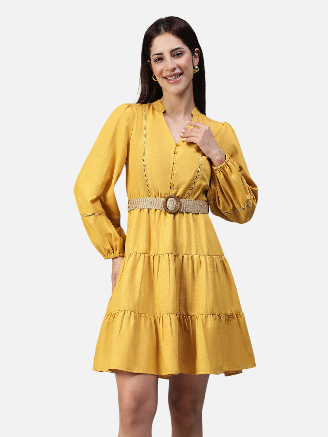 Woman wearing a mustard yellow tiered mini dress with long sleeves and belted waist