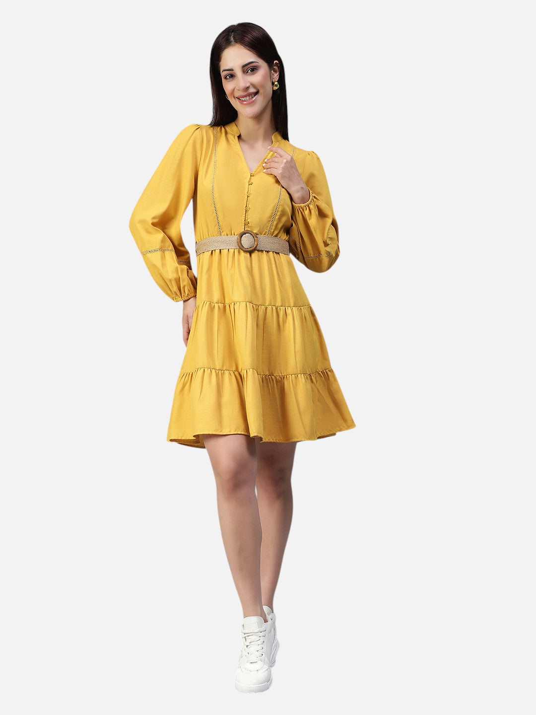 Woman wearing yellow belted tiered mini dress with long sleeves and white sneakers