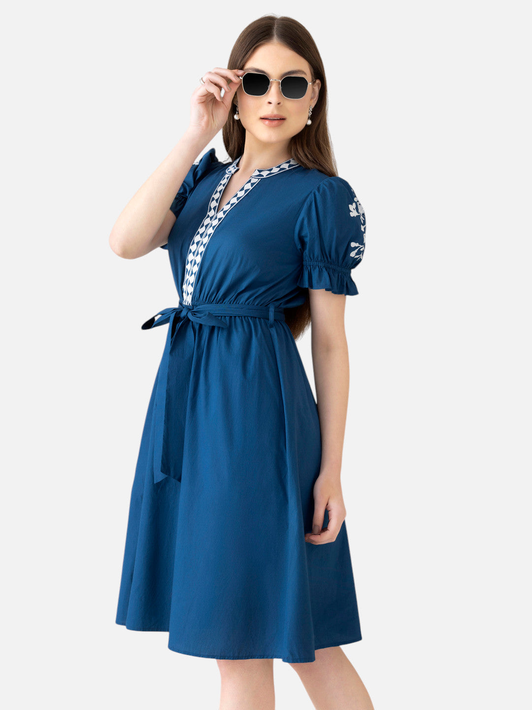 Woman wearing blue knee-length dress with puff sleeves, white trim, and sunglasses