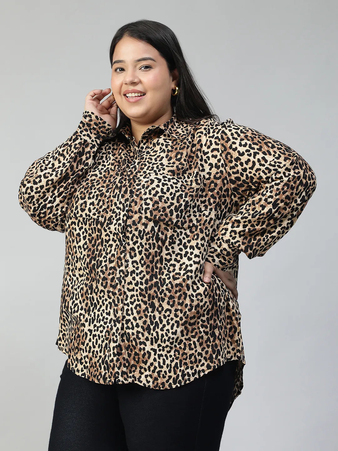 A woman with long dark hair is smiling and posing in a leopard print shirt.