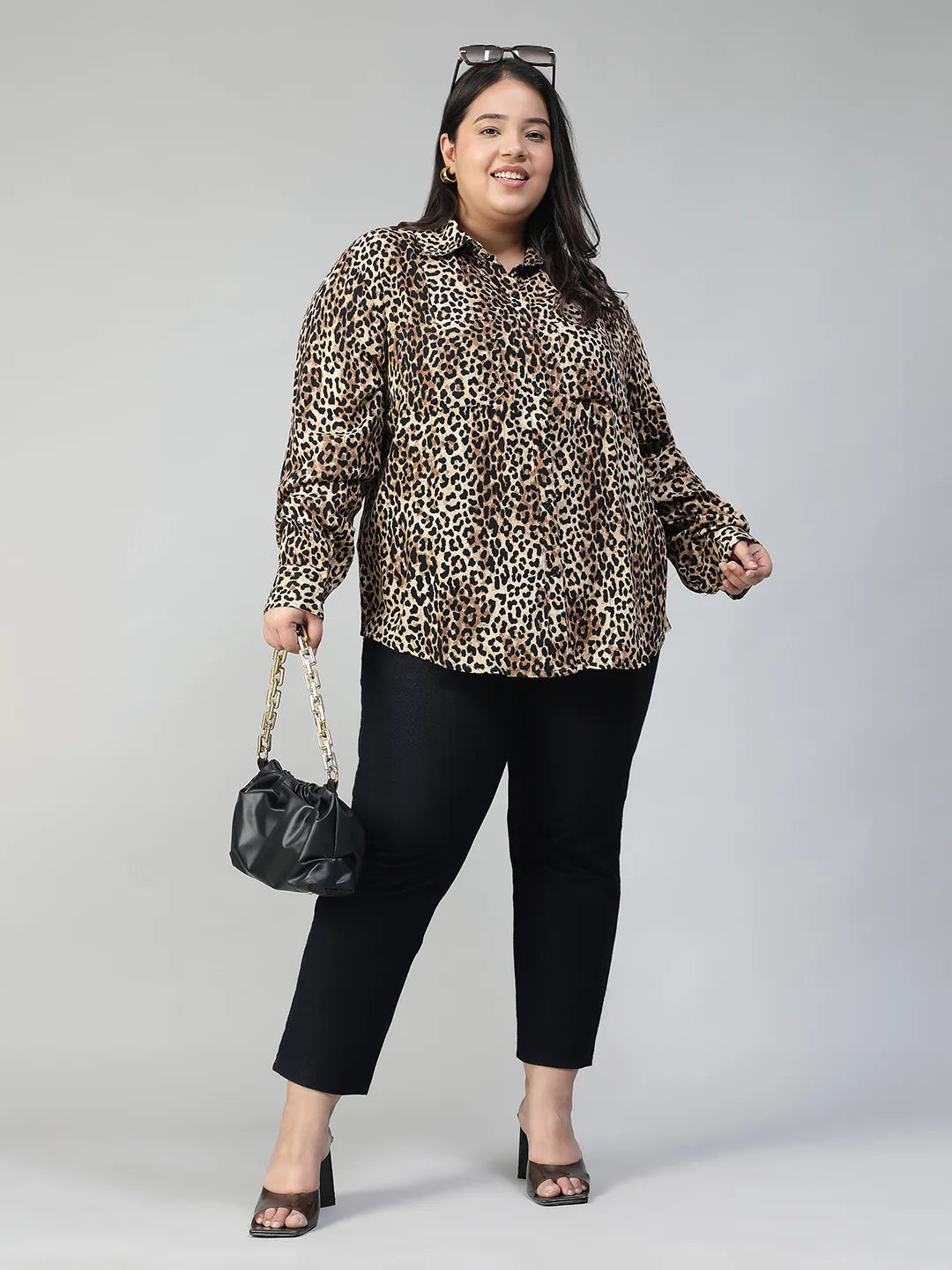 A woman with long dark hair is smiling and posing in a leopard print shirt.
