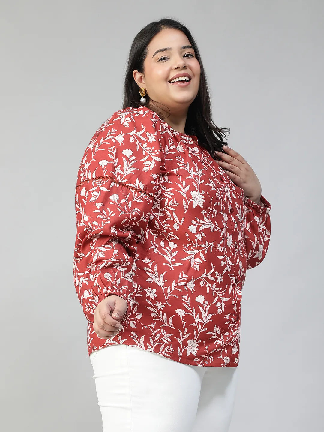 A woman wearing a red and white floral blouse with long sleeves, smiling at the camera.