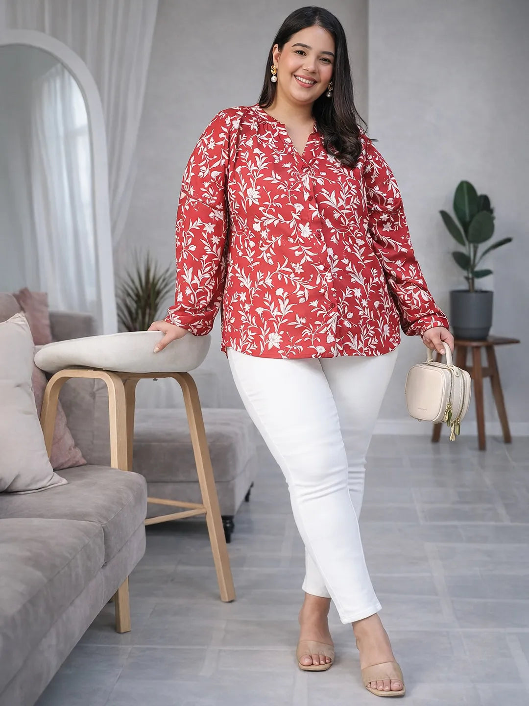 A woman wearing a red and white floral blouse with long sleeves, smiling at the camera.