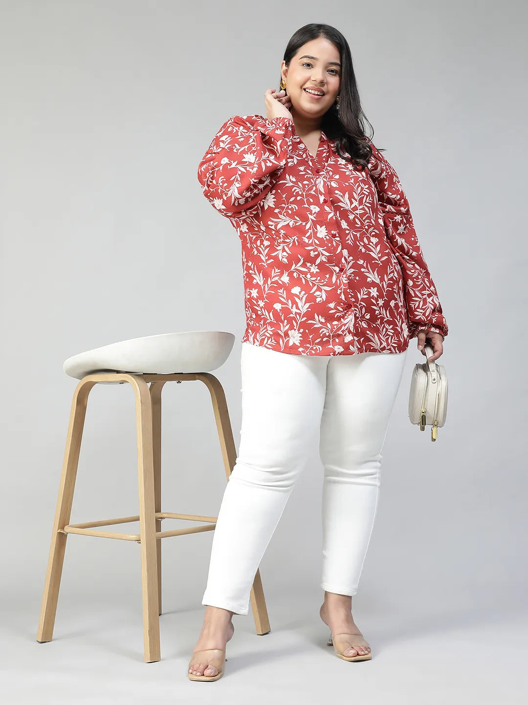 A woman wearing a red and white floral blouse with long sleeves, smiling at the camera.