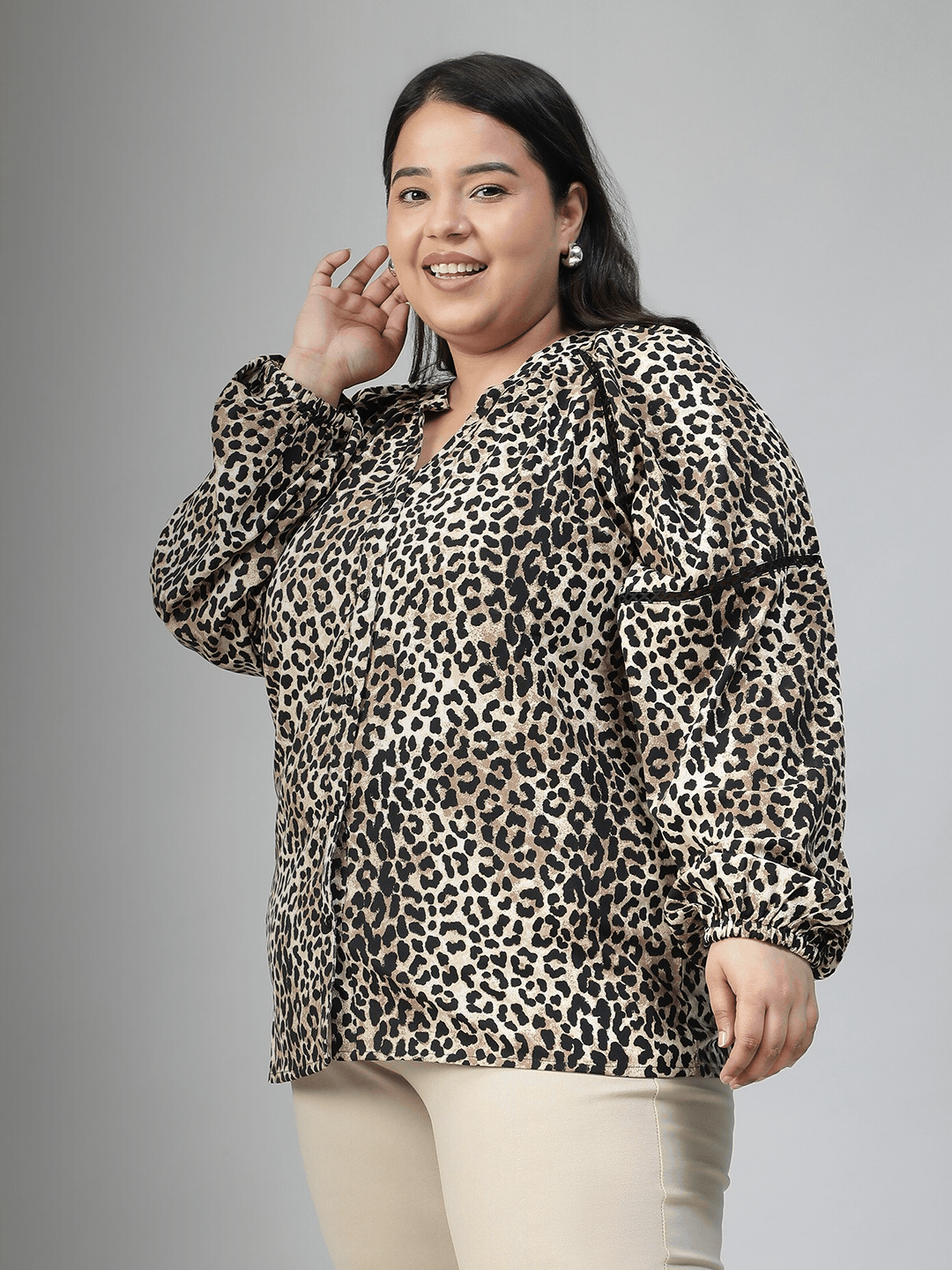 A smiling woman wearing a leopard print blouse with long sleeves.