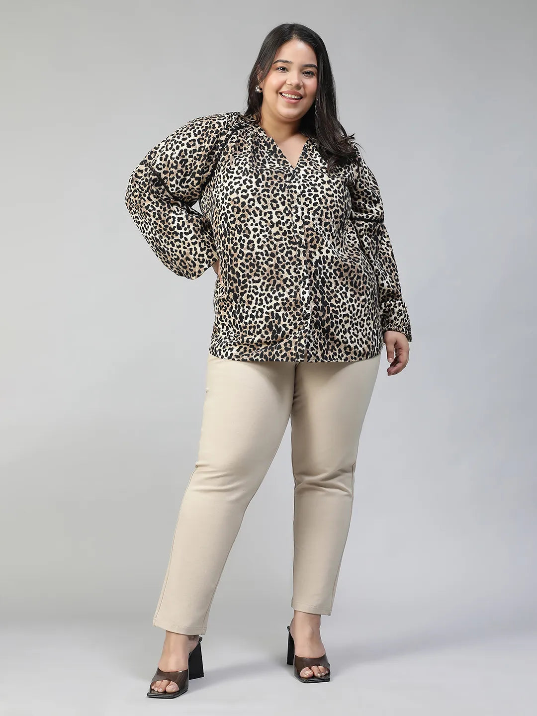 A smiling woman wearing a leopard print blouse with long sleeves.
