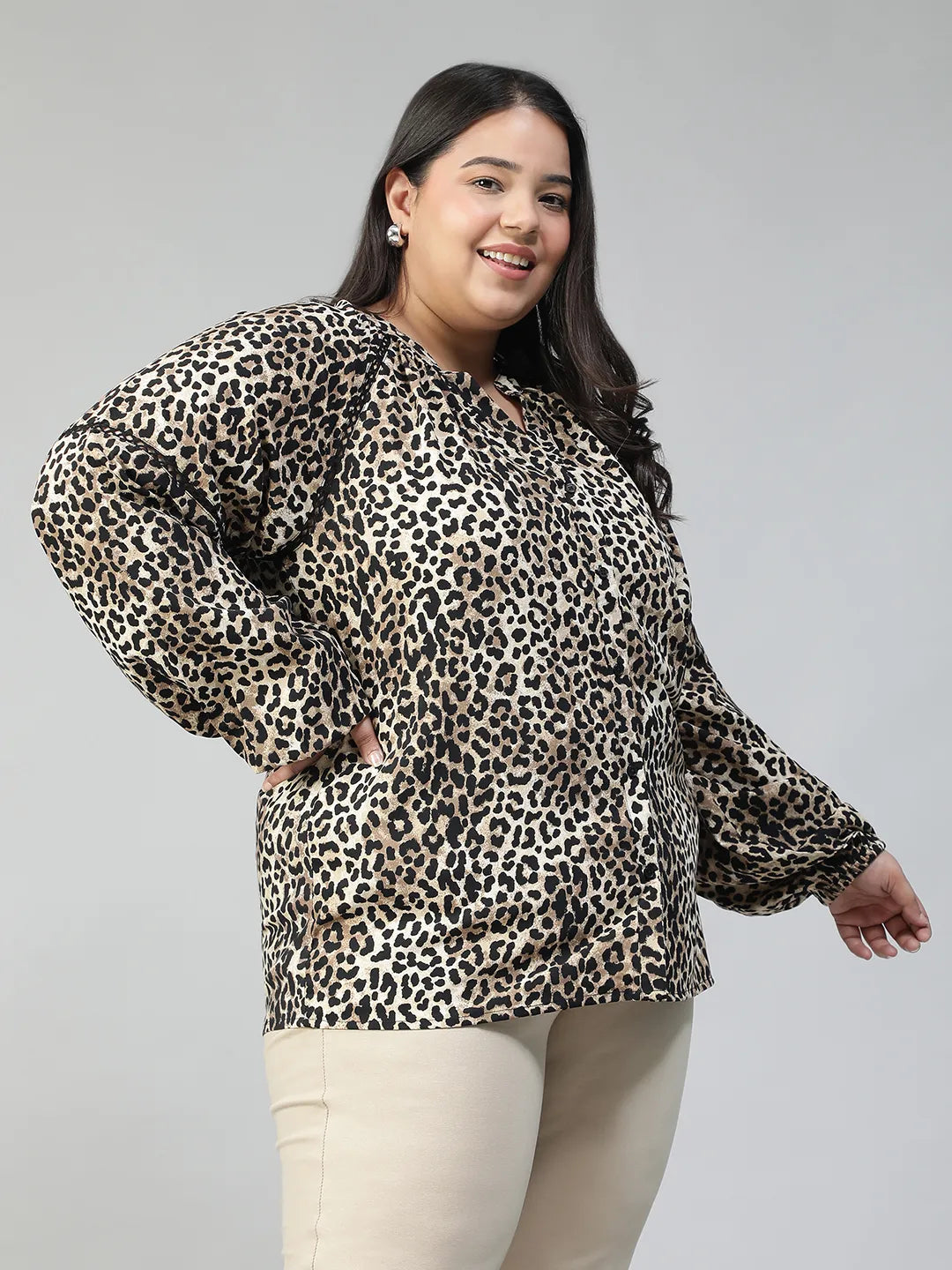 A smiling woman wearing a leopard print blouse with long sleeves.