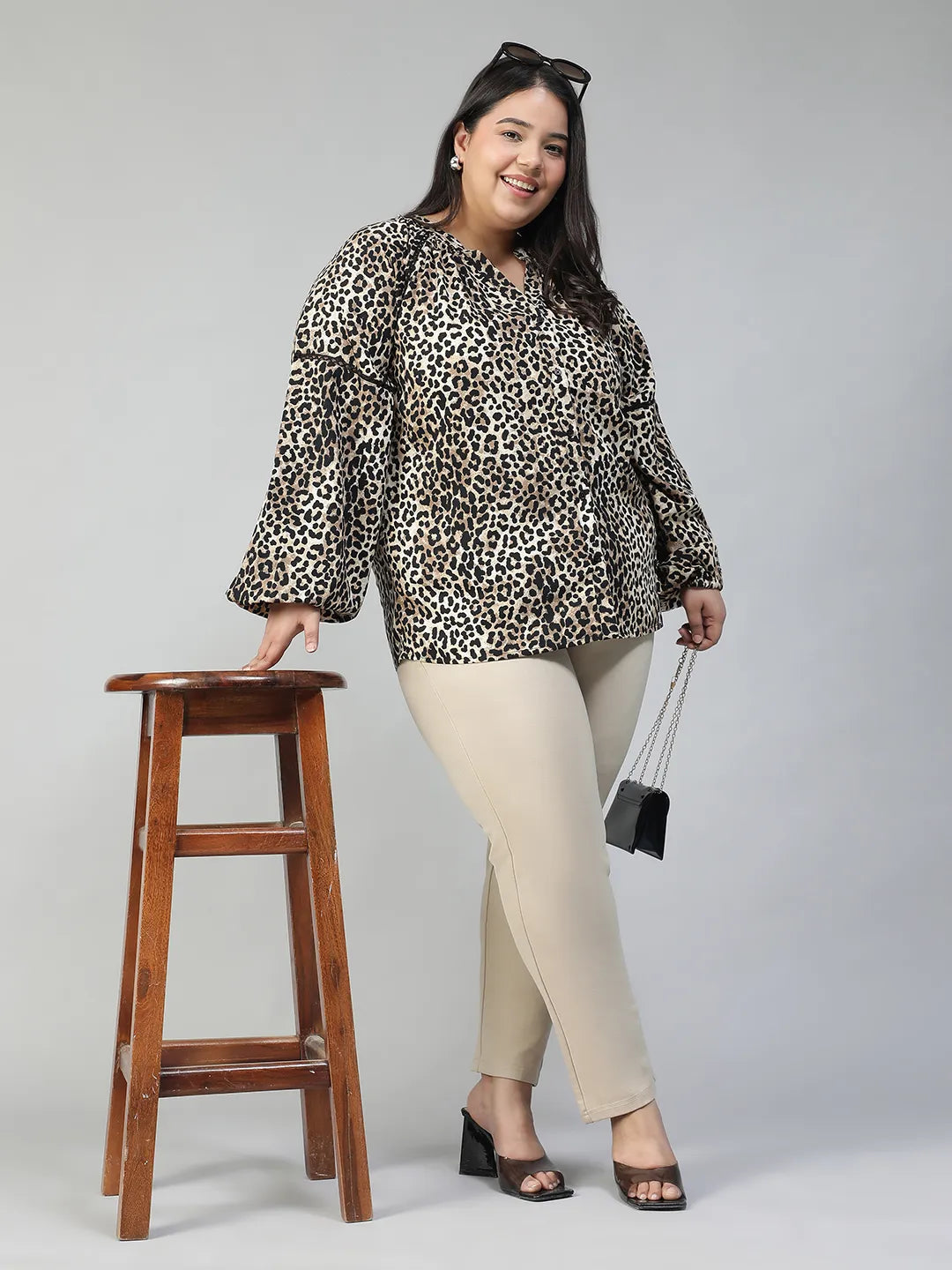 A smiling woman wearing a leopard print blouse with long sleeves.