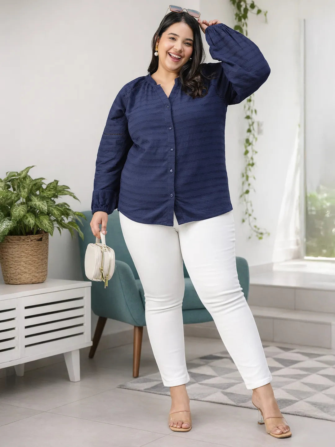 A woman with long dark hair is smiling and wearing a navy blue blouse with a v-neck and button-down sleeves.