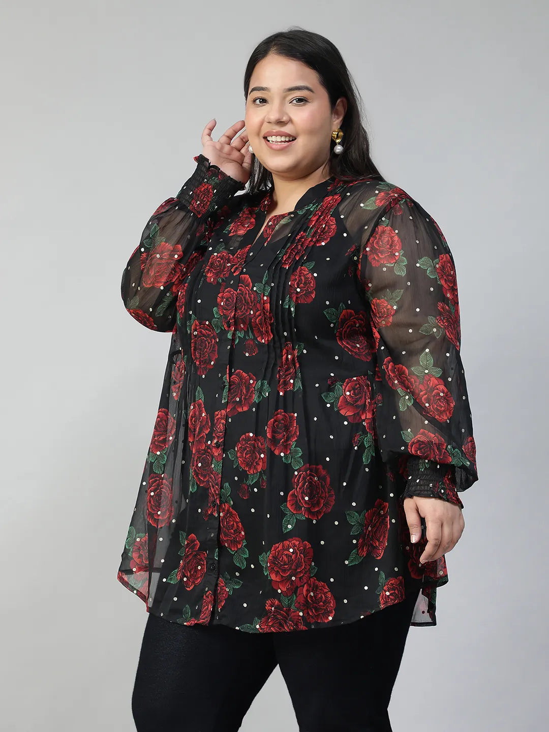 A woman wearing a black and red floral blouse with a high collar and puffed sleeves, smiling at the camera.