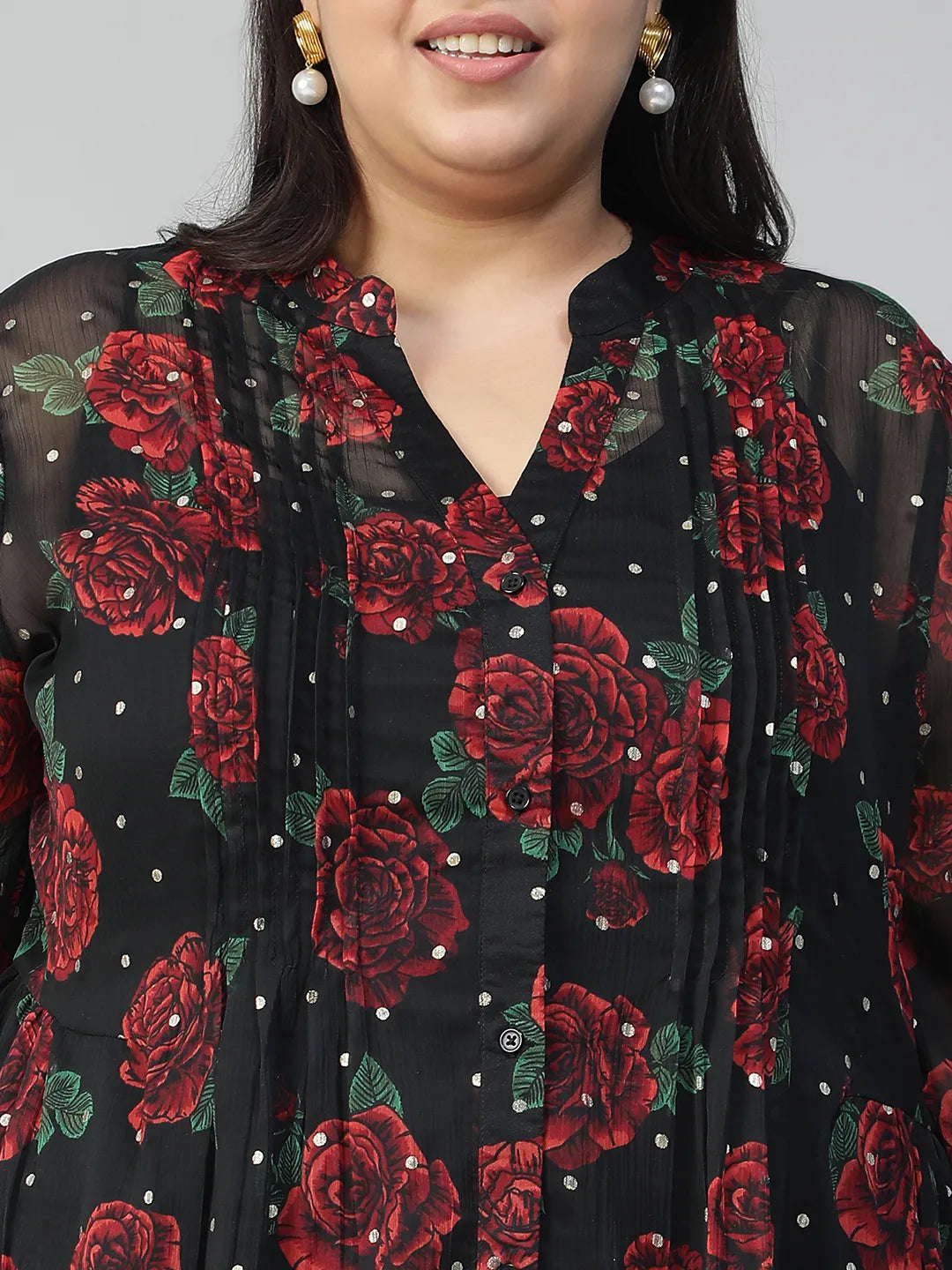 A woman wearing a black and red floral blouse with a high collar and puffed sleeves, smiling at the camera.