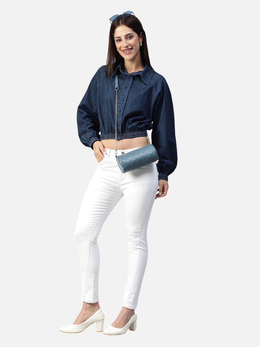 Woman modeling a blue denim cropped jacket with white skinny jeans and white heels