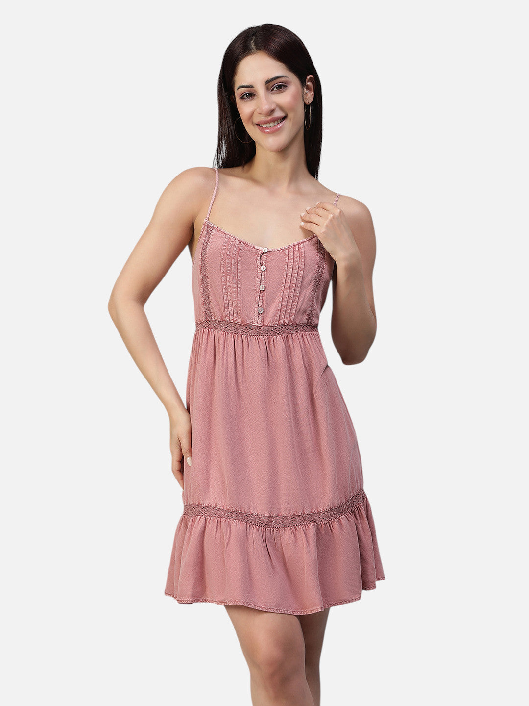 Woman wearing a sleeveless pink ruffle mini dress with thin straps and button detail