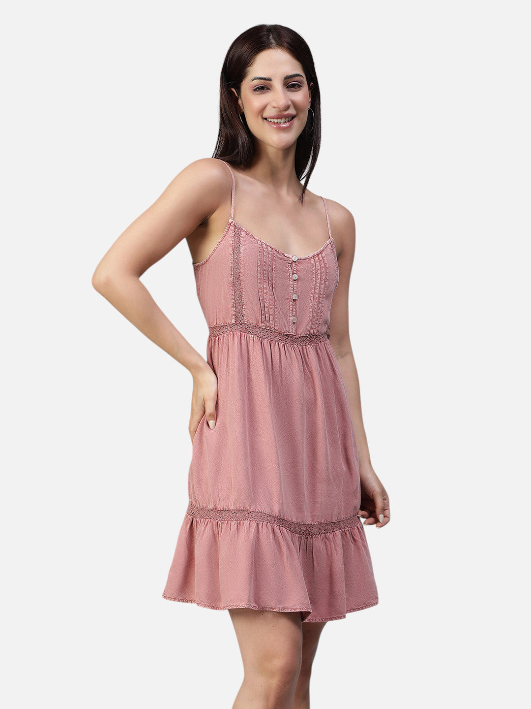 Woman wearing a sleeveless pink mini dress with lace trim and button details