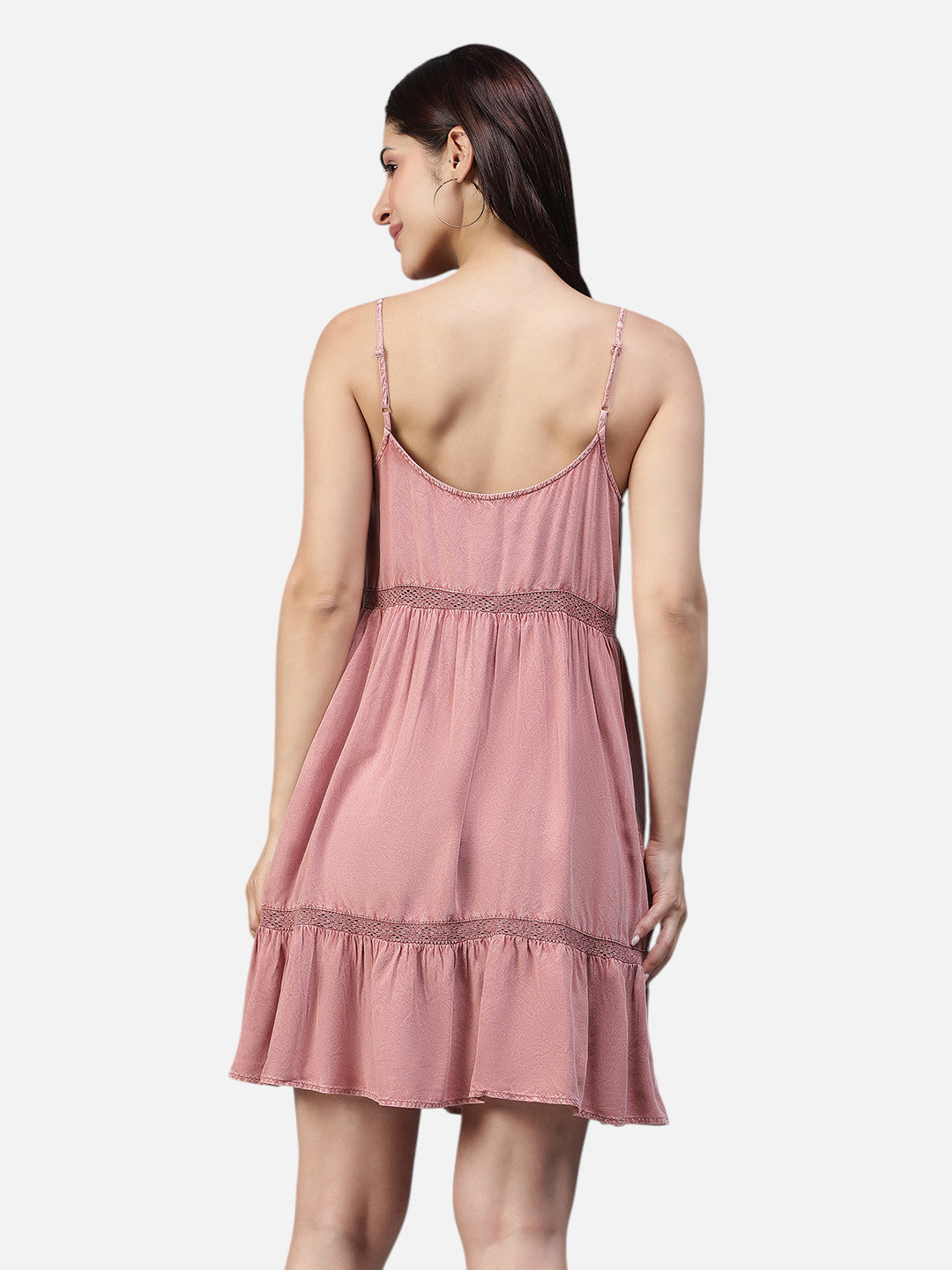 Woman wearing a pink sleeveless mini dress with spaghetti straps, back view