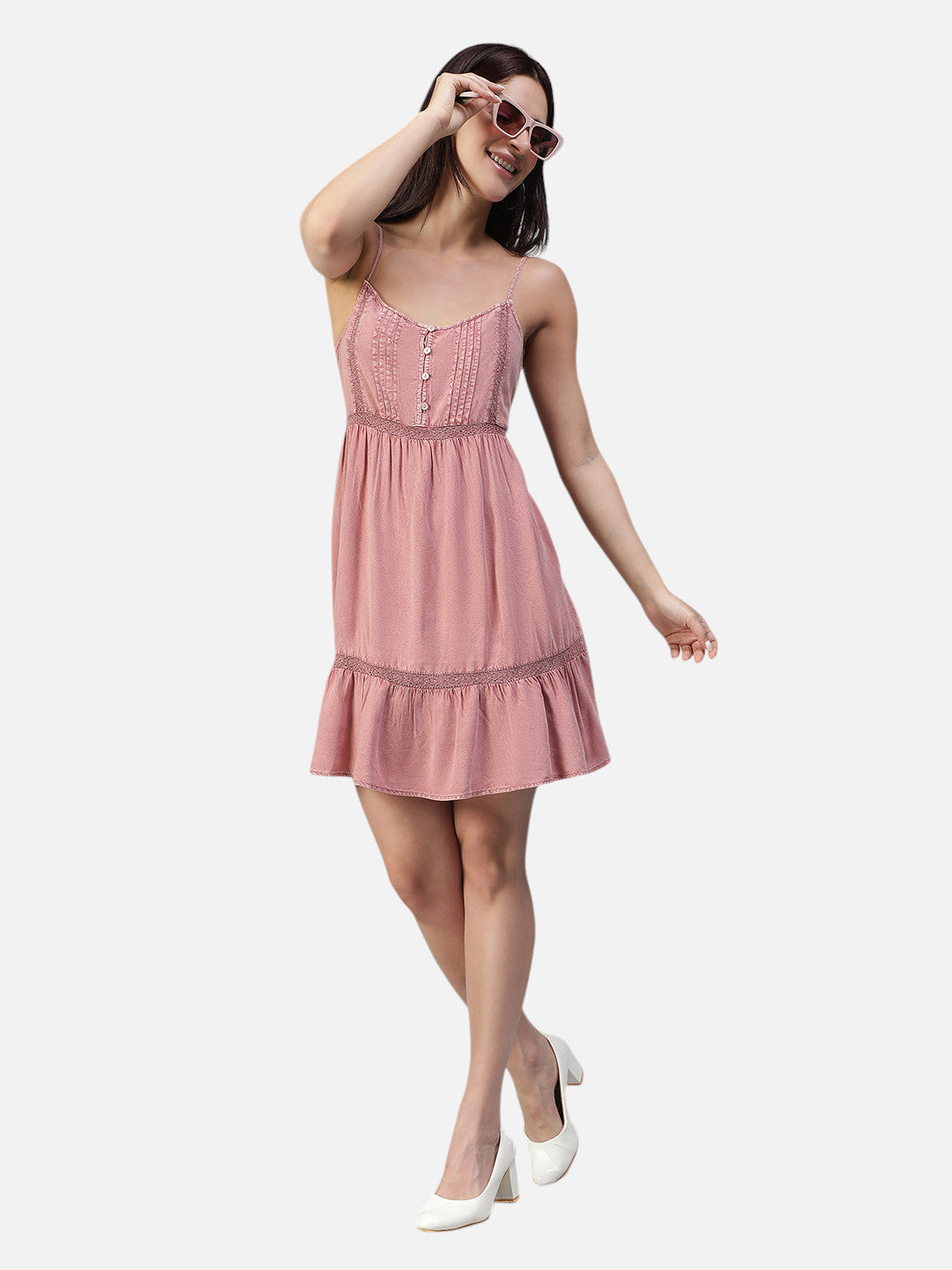 Woman in a pink sleeveless mini dress with lace details, white heels, and sunglasses